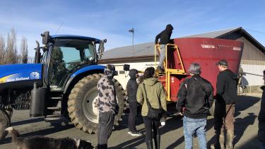 Highschool Students standing and looking at blue tractor