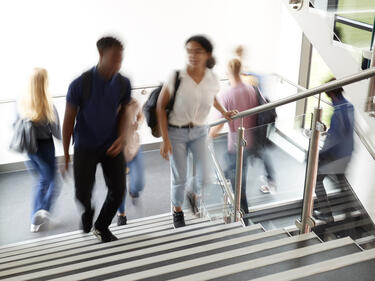 Motion Blur Shot Of High School Students Walking On Stairs Between Lessons In Busy College Building