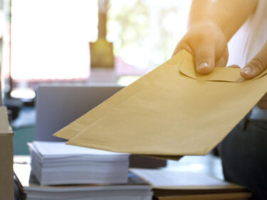 Office clerk or secretary handing over documents and brown envelopes